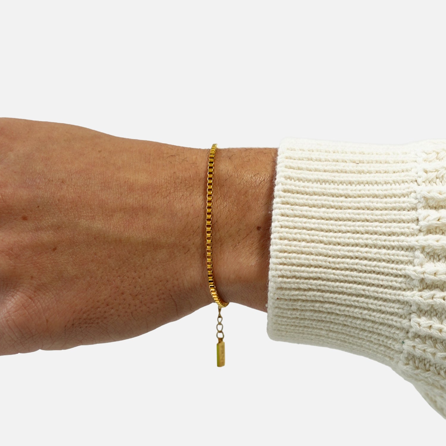 Gold box chain bracelet worn on wrist with adjustable extension chain on a clean white background