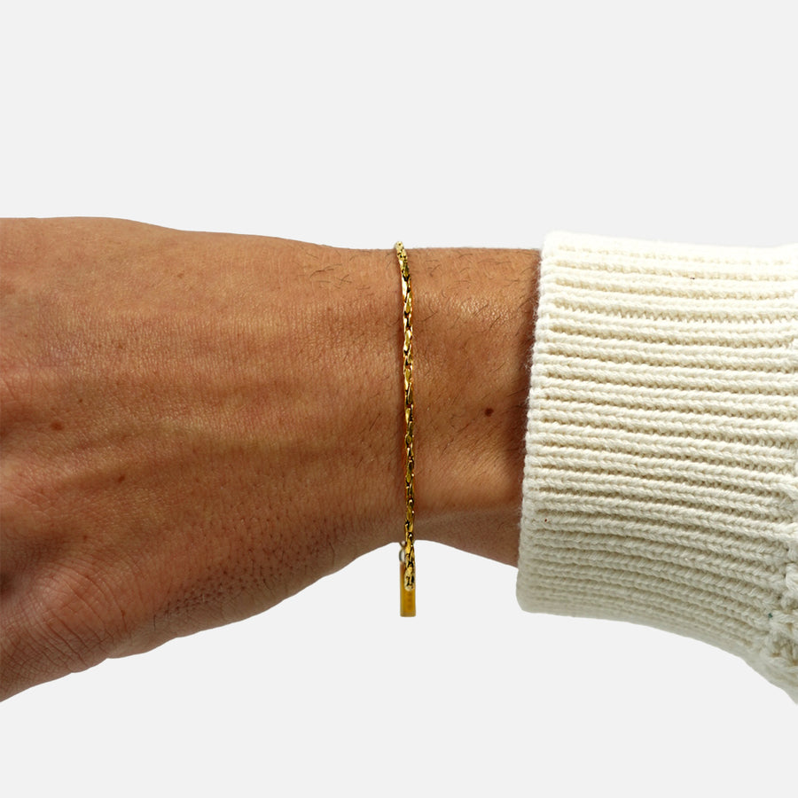 Gold refined round rope bracelet worn on wrist with extension chain on white background