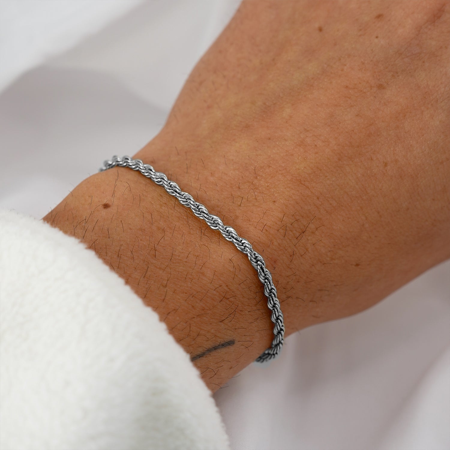 Close-up of silver rope bracelet worn on wrist with soft blurred background