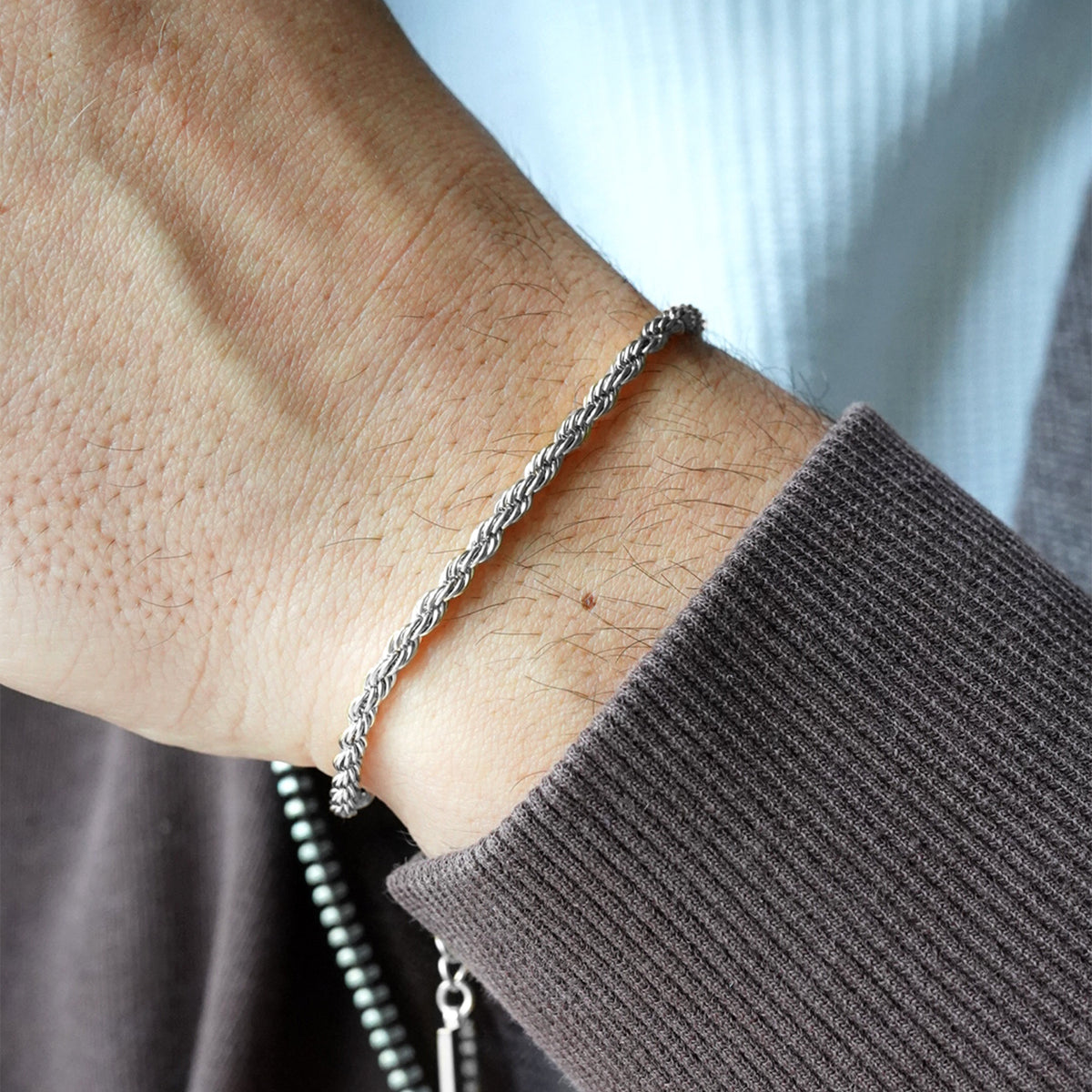 Silver rope chain bracelet by FRNE worn on wrist with dark sleeve