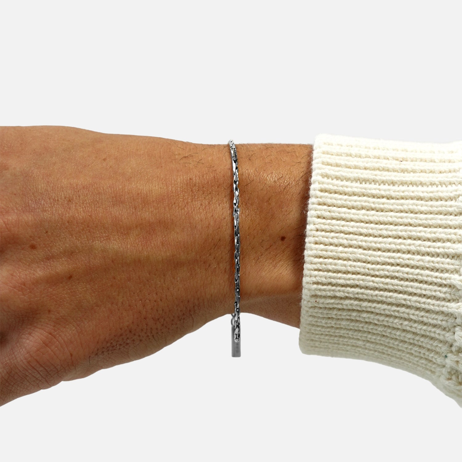 Silver round rope chain bracelet worn on wrist with extension chain and neutral background