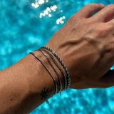 Premium silver snake chain bracelet by FRNE stacked with other bracelets on wrist poolside lifestyle