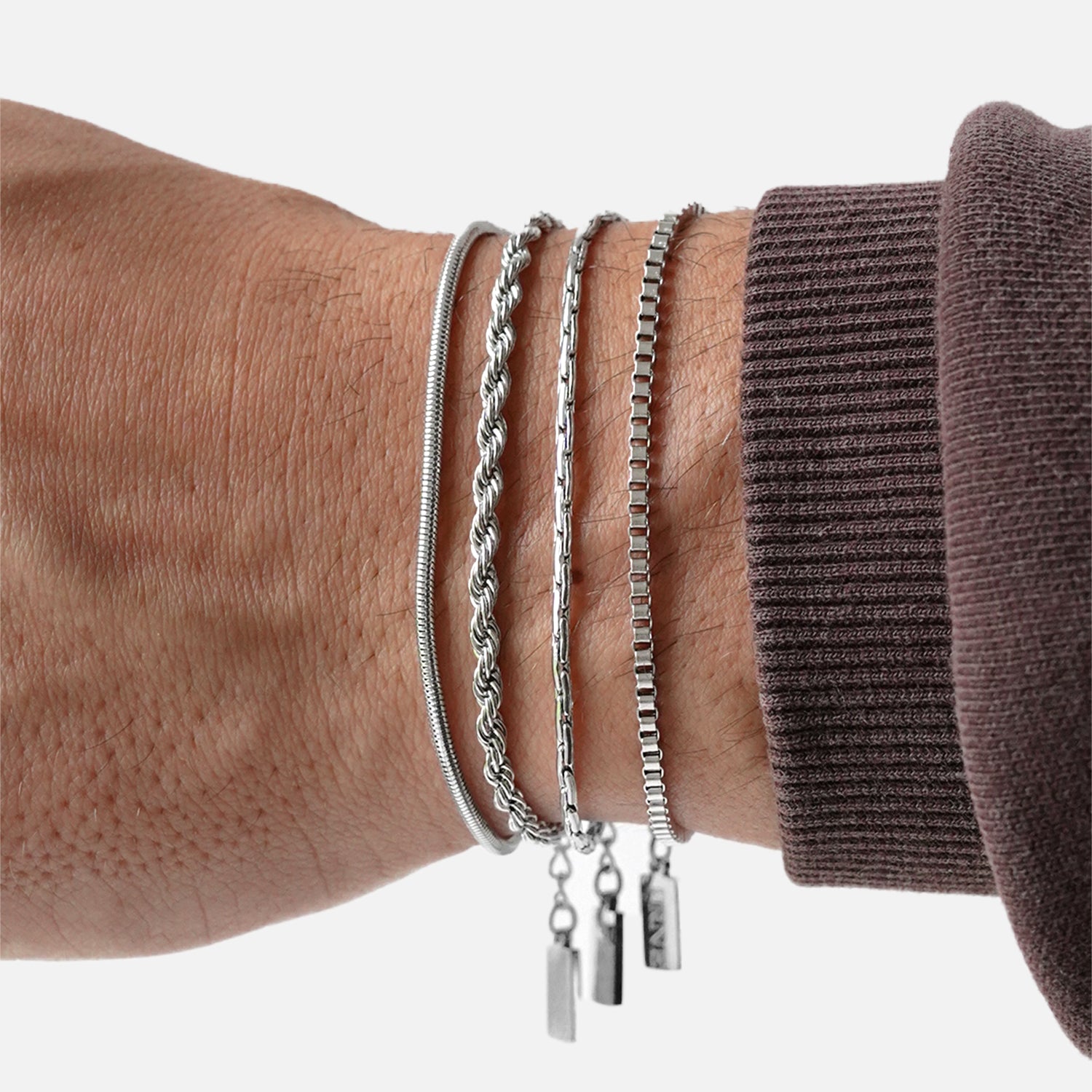 Premium silver snake chain bracelet by FRNE stacked with other bracelets on wrist minimalist styling