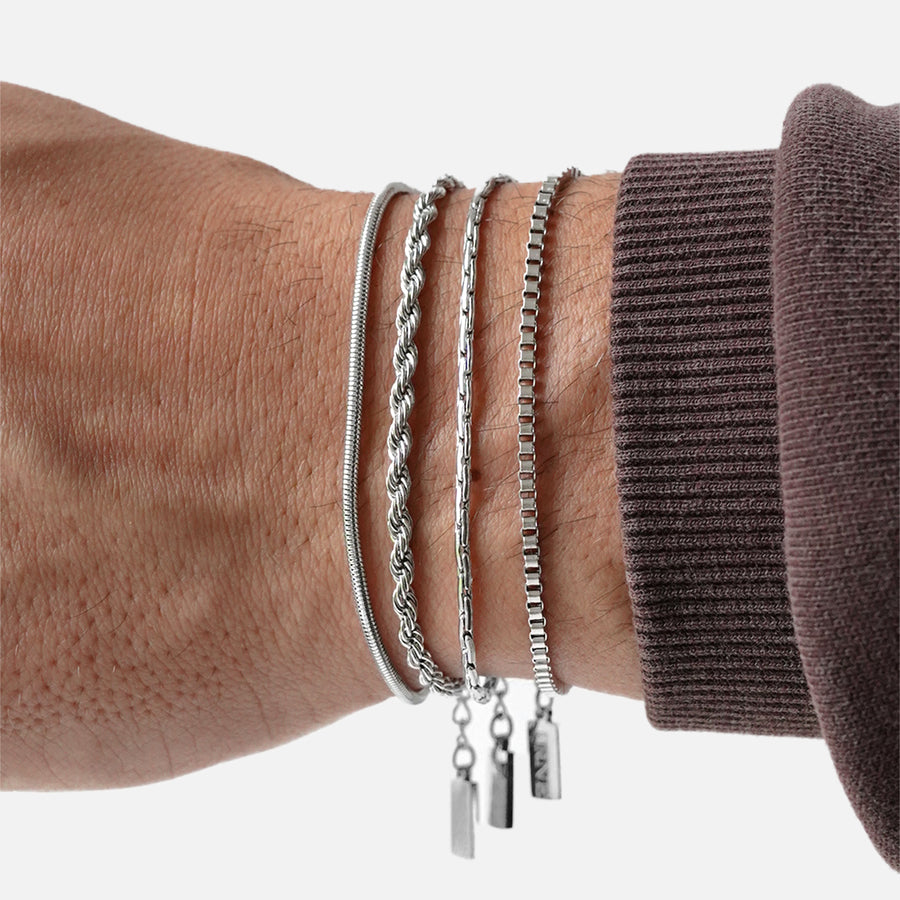 Premium silver snake chain bracelet by FRNE stacked with other bracelets on wrist minimalist styling