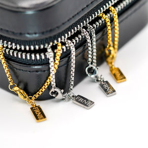 Gold and silver necklaces with 'FRNE' charms on a black zippered case.