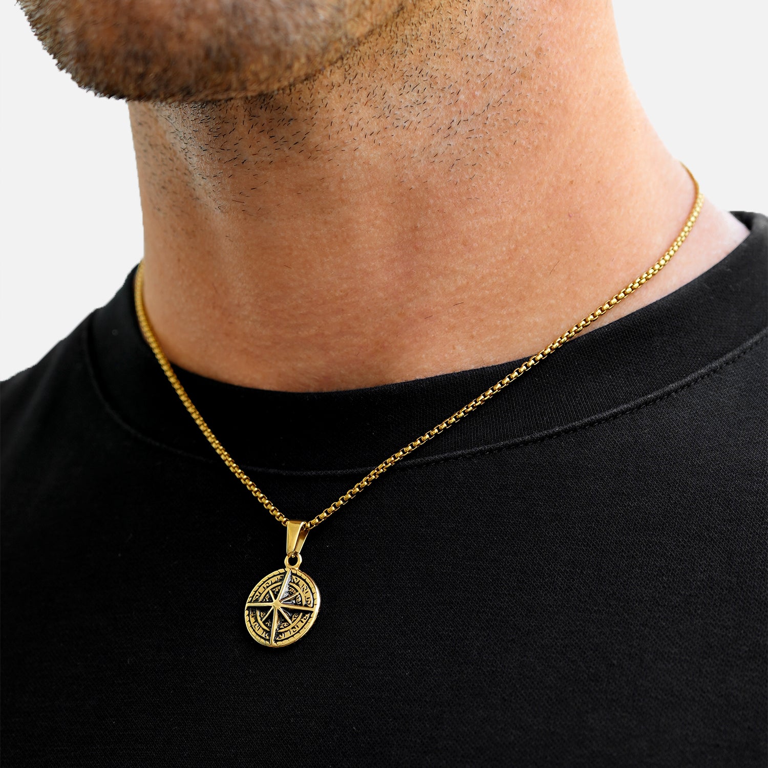 Gold necklace with a pendant worn by a person on a plain background