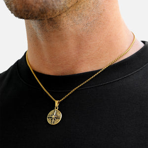 Gold necklace with a pendant worn by a person on a plain background