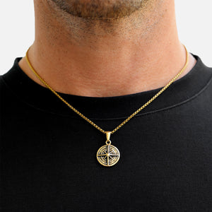 Gold necklace with a compass pendant worn by a person on a black shirt background
