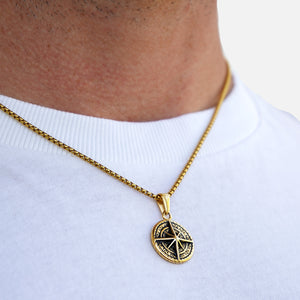 Gold necklace with a pendant on a person wearing a white shirt
