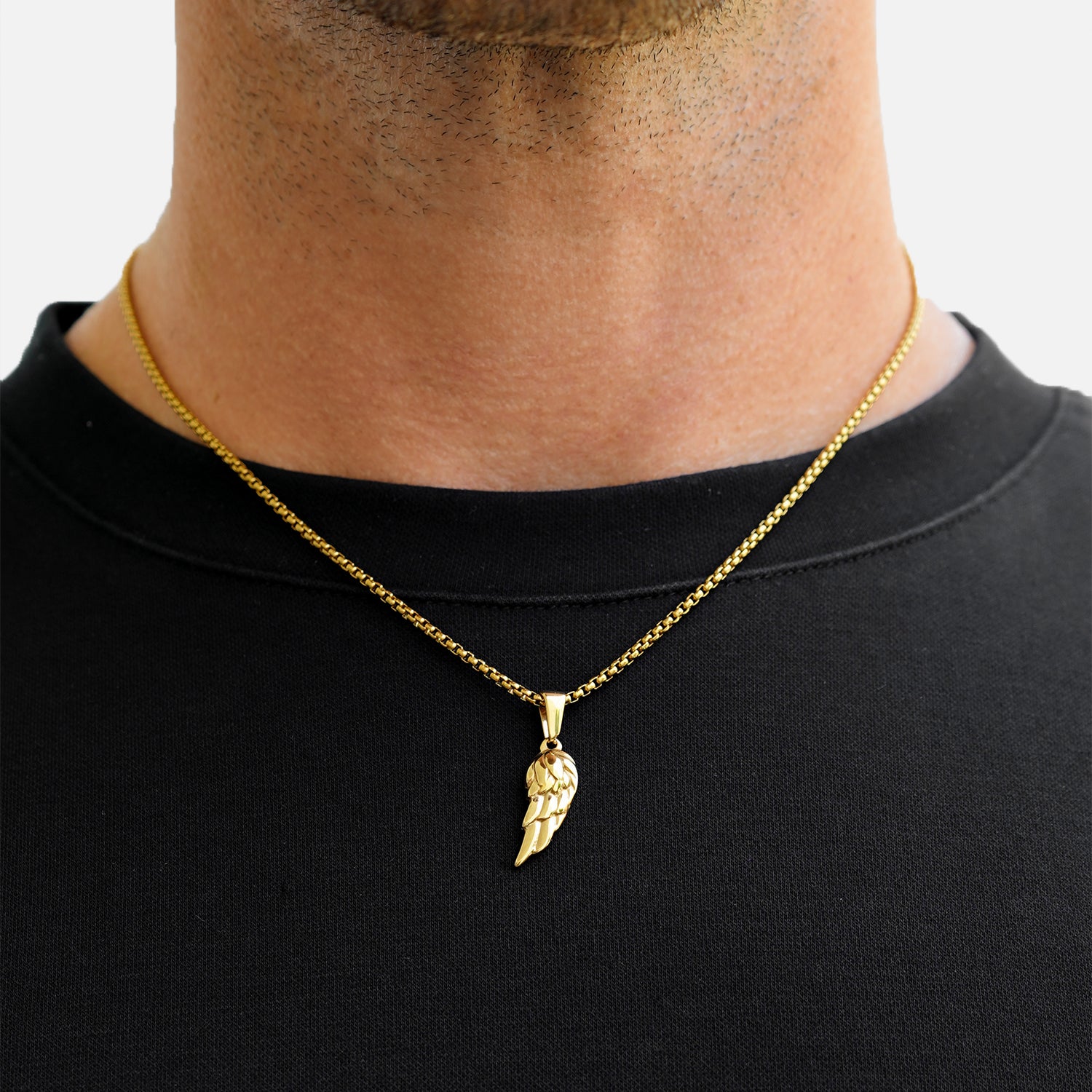 Gold necklace with a pendant worn by a person on a plain background