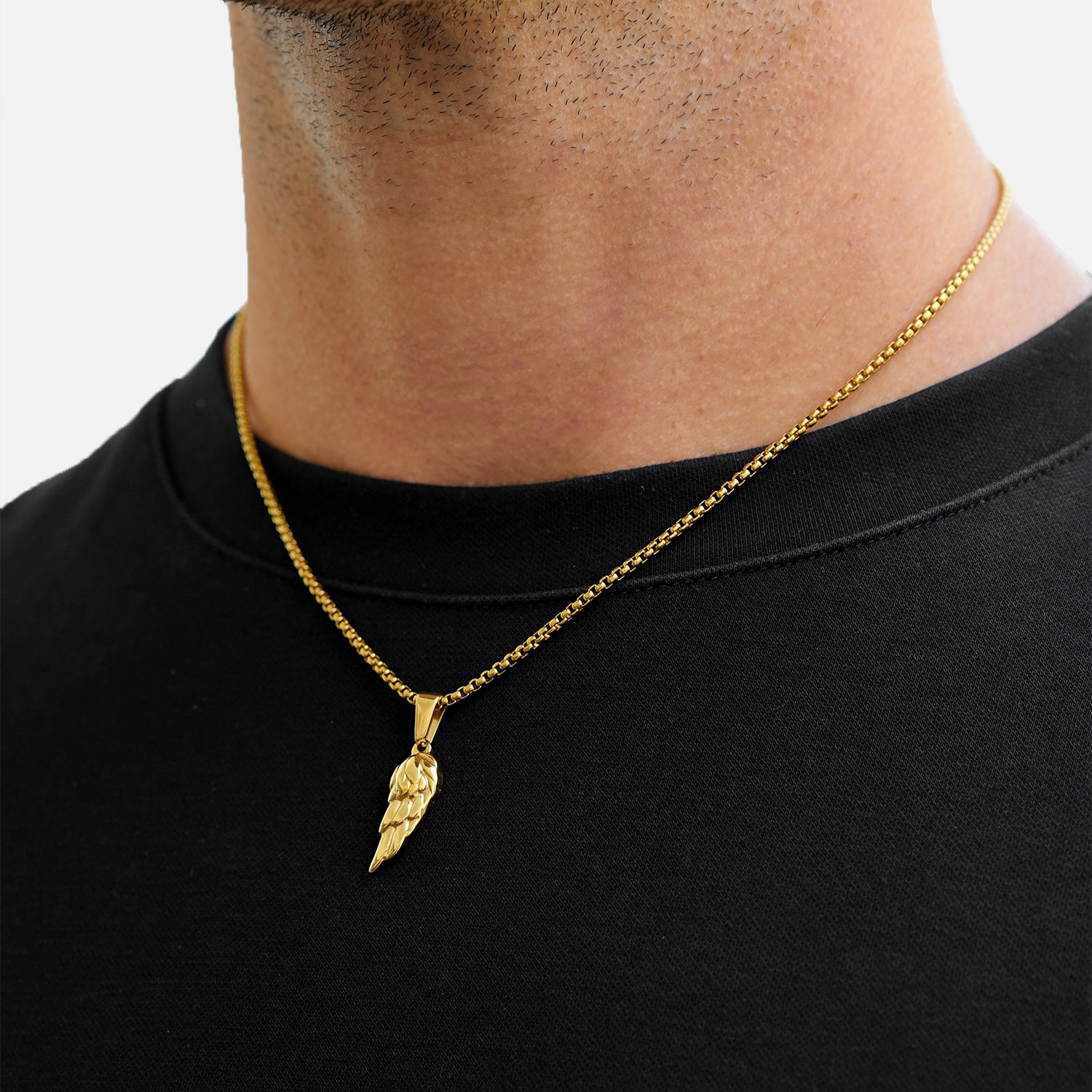 Gold necklace with a pendant worn by a person on a plain background
