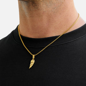 Gold necklace with a pendant worn by a person on a plain background