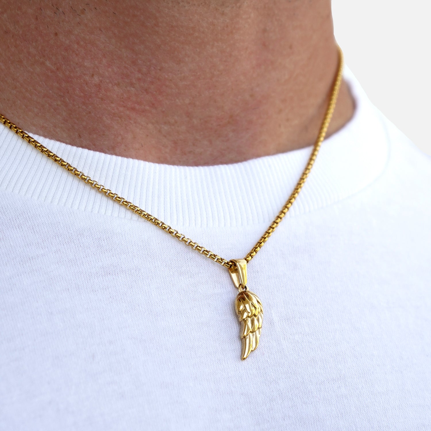 Gold necklace with a wing pendant on a white shirt