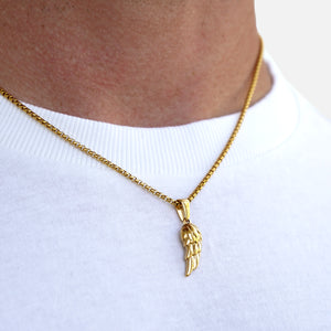 Gold necklace with a wing pendant on a white shirt