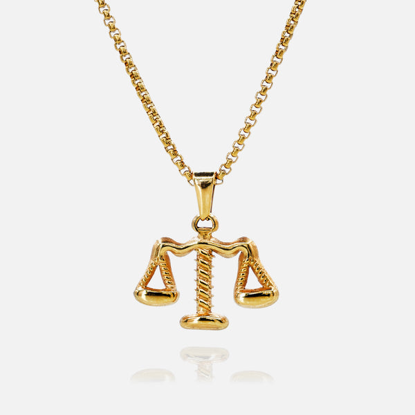 Gold necklace with a Libra scale pendant on a white background