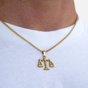 Gold Libra zodiac pendant necklace on a white shirt