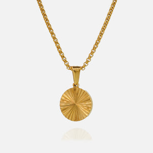 Gold necklace with a round pendant on a light gray background