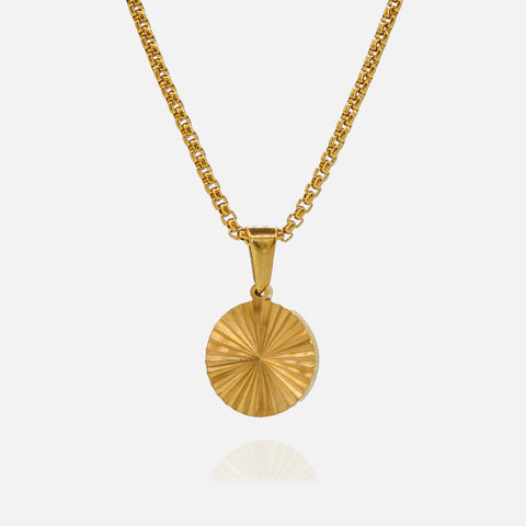 Gold necklace with a round pendant on a light gray background