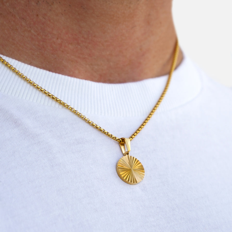 Gold necklace with a circular pendant on a white background