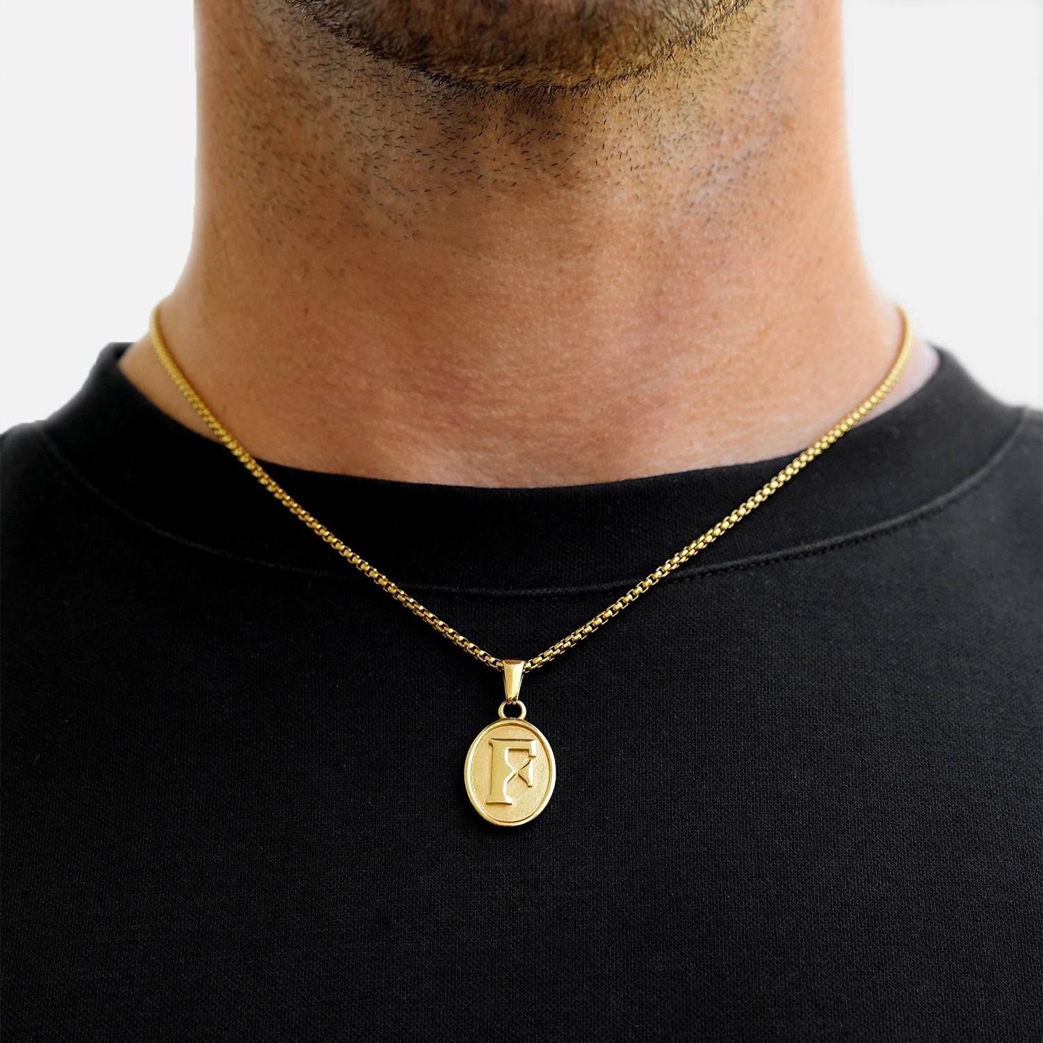 Gold necklace with a pendant worn by a person on a plain background