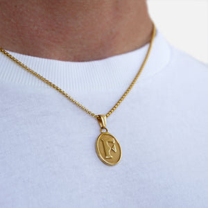Gold necklace with a pendant on a white shirt