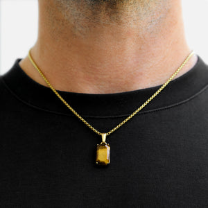 Gold necklace with a pendant worn by a person on a plain background