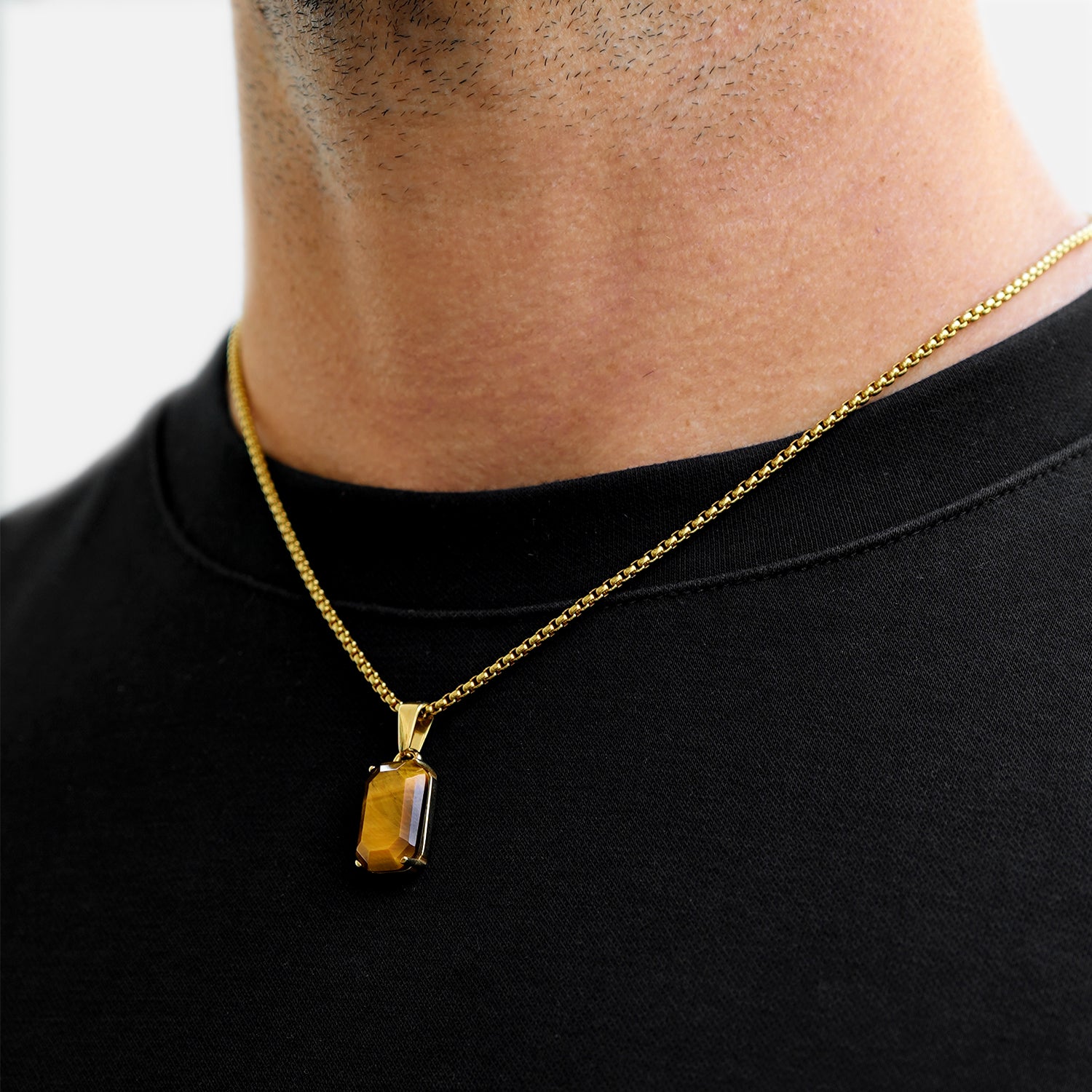 Gold necklace with a pendant worn by a person on a black background