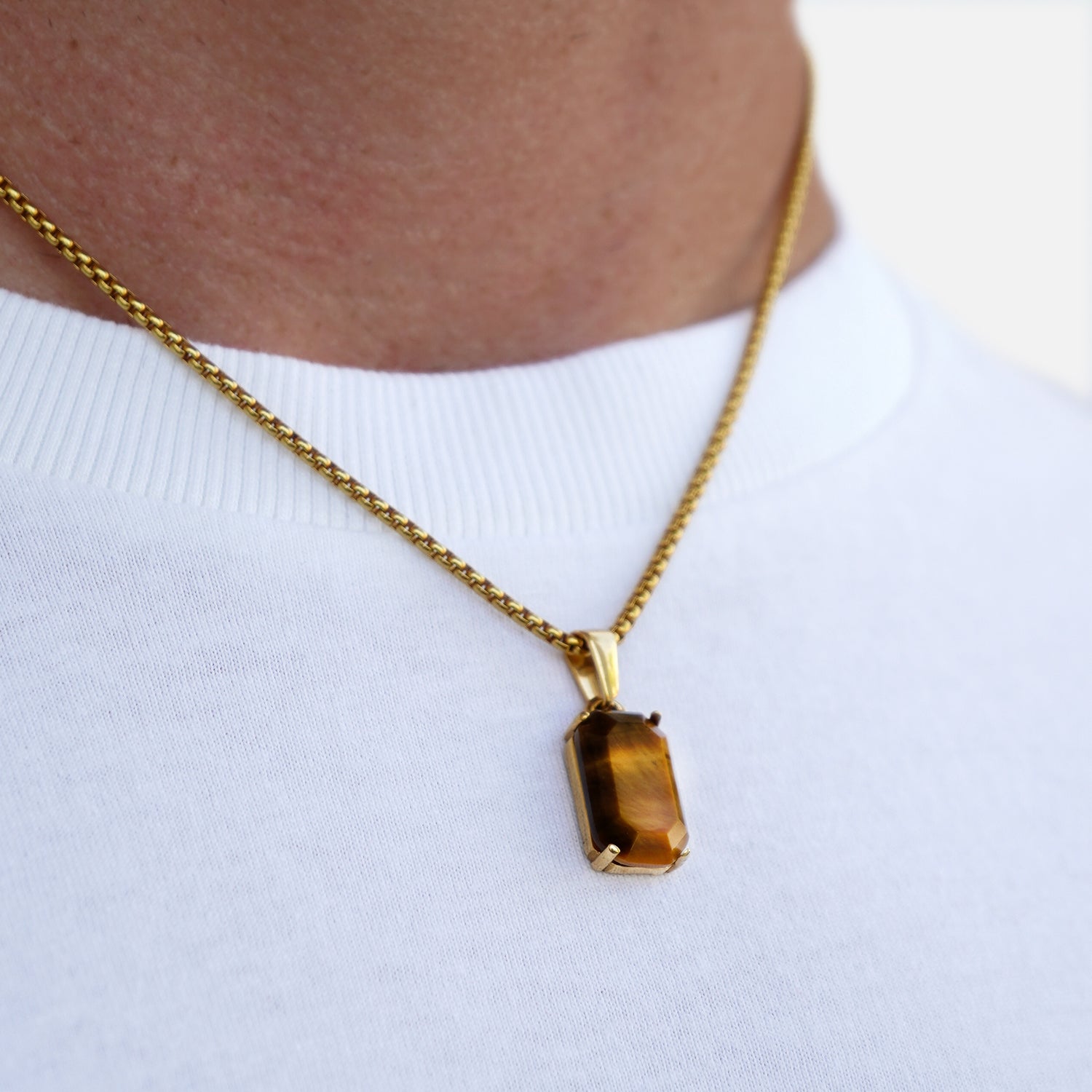 Gold necklace with a brown pendant on a white background