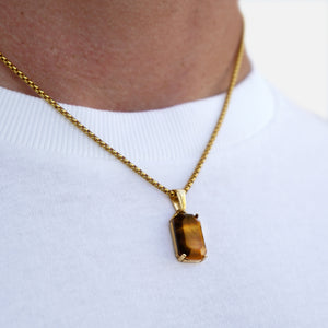 Gold necklace with a brown pendant on a white background