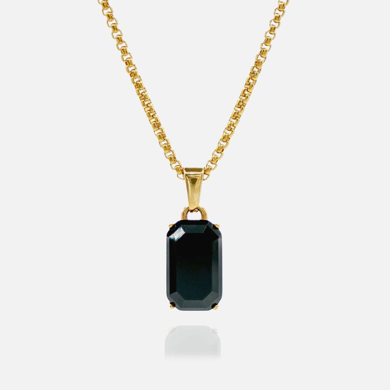 Gold necklace with a black gemstone pendant on a white background