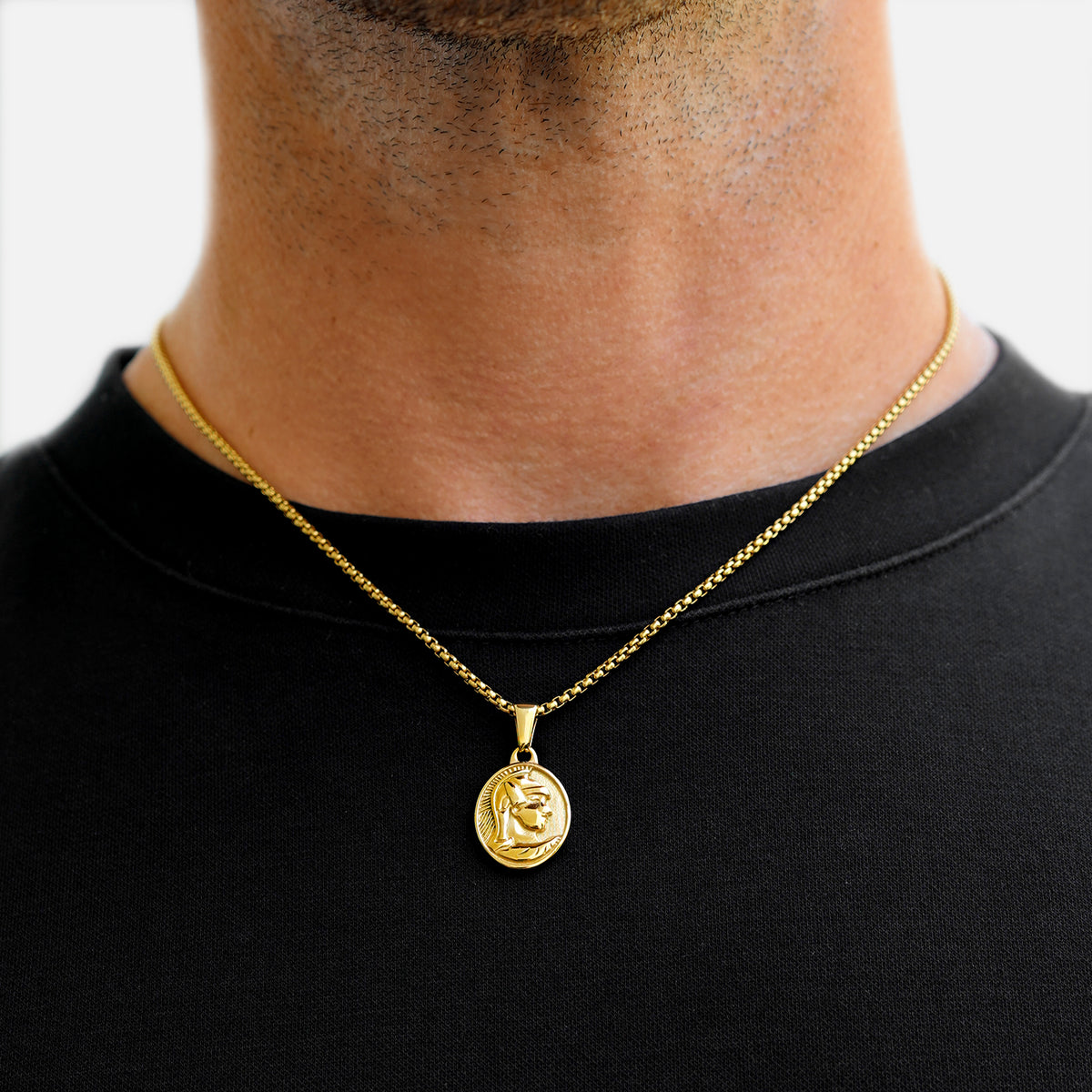 Gold necklace with a pendant on a person wearing a black shirt