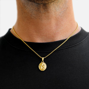 Gold necklace with a pendant on a person wearing a black shirt