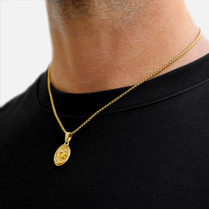 Gold necklace with a pendant on a person wearing a black shirt against a white background