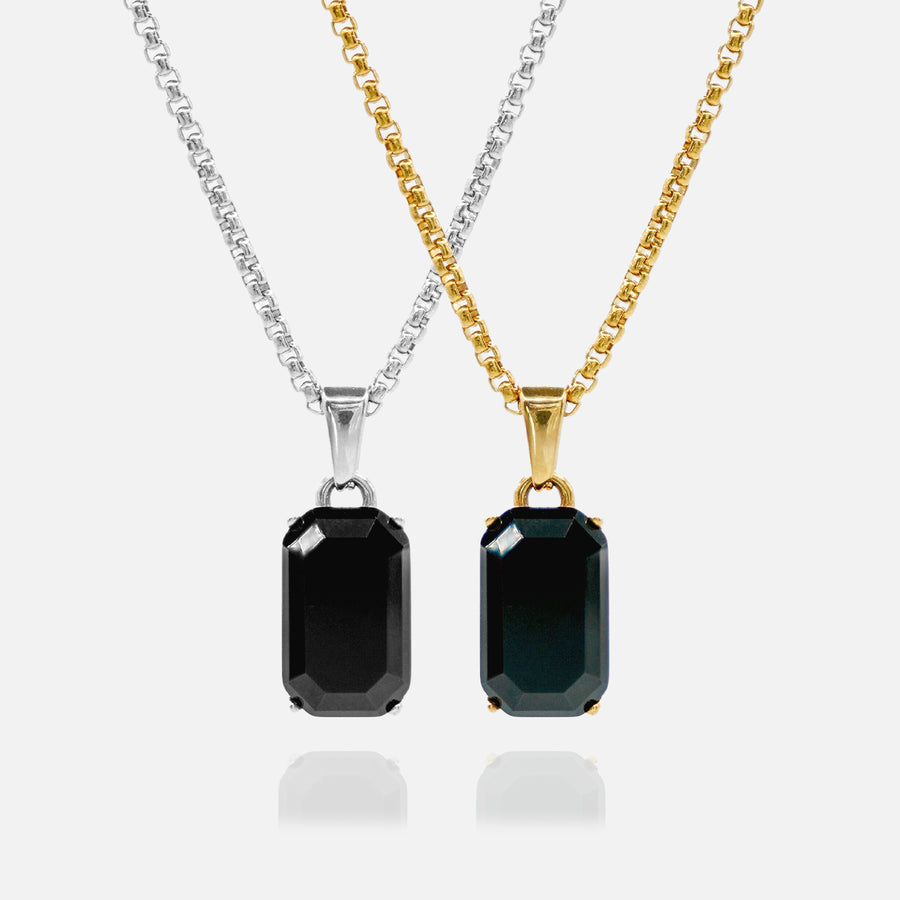Two black gemstone pendants on gold and silver chains against a white background