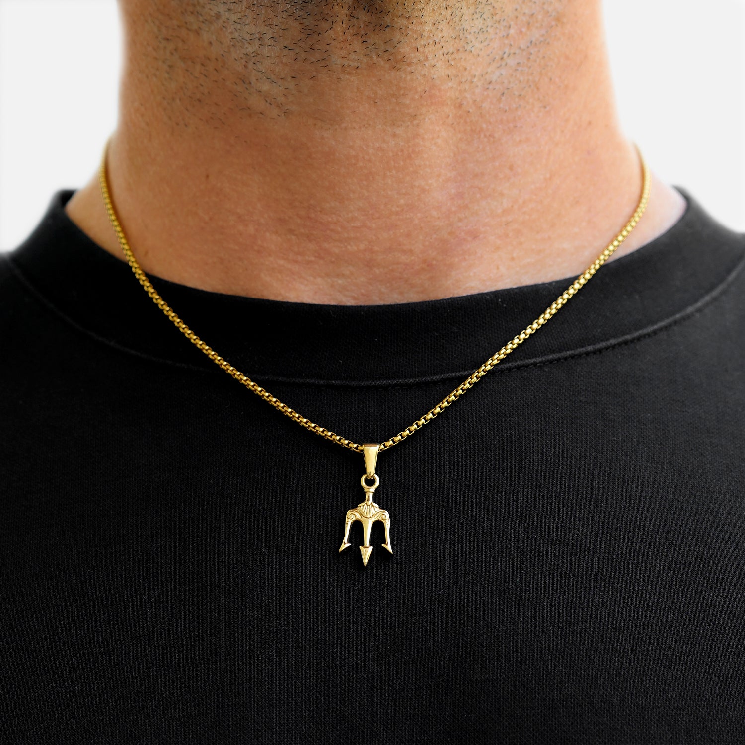 Gold necklace with a pendant on a black shirt against a white background