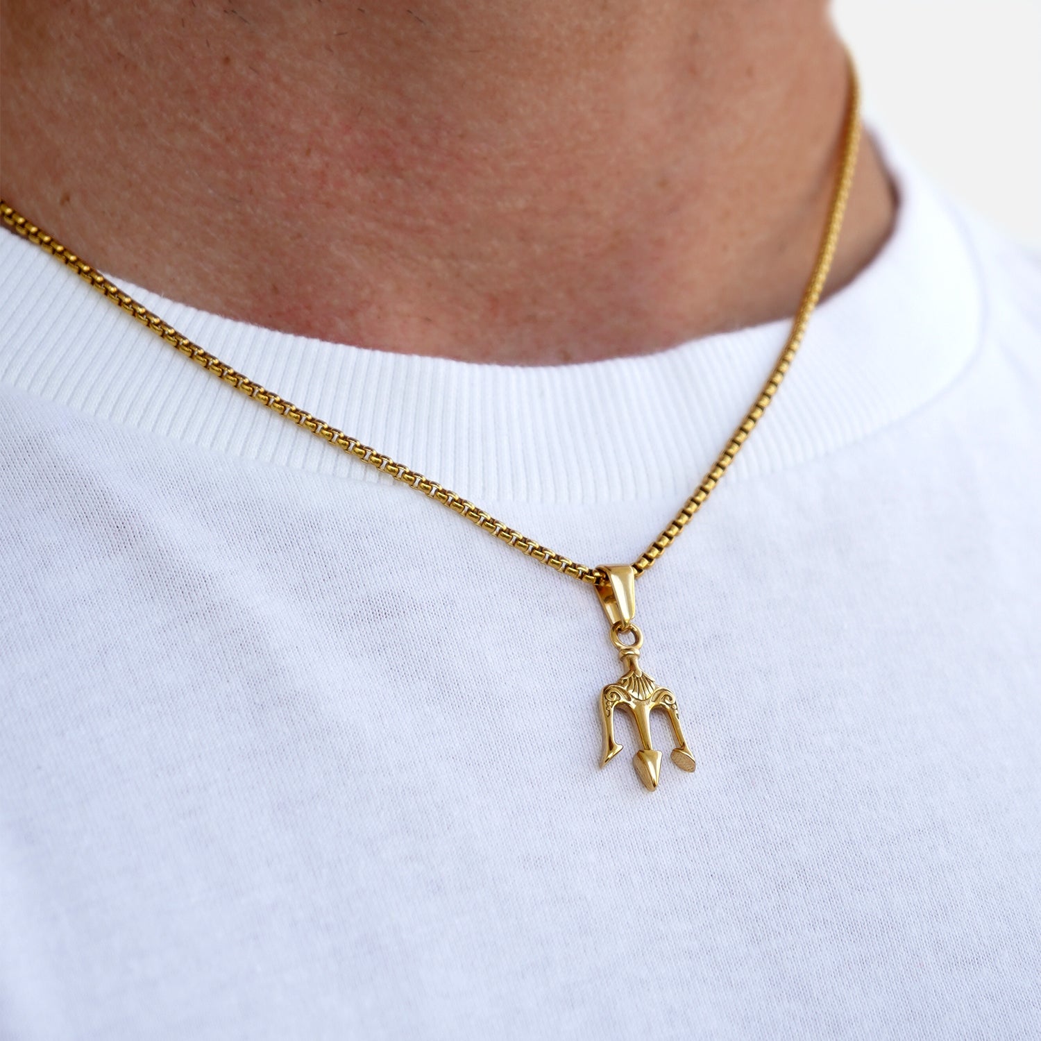 Gold necklace with a small pendant on a white shirt