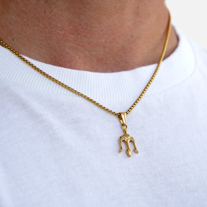 Gold necklace with a small pendant on a white shirt