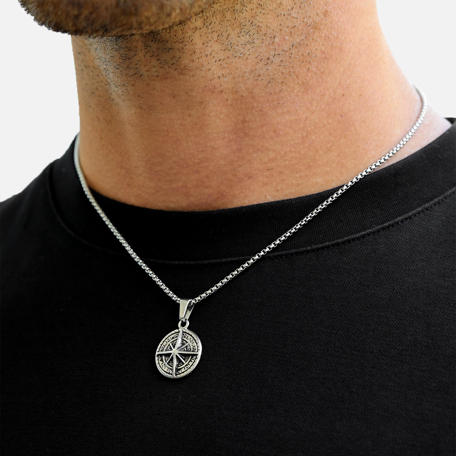Person wearing a black shirt with a silver necklace featuring a pentacle pendant.
