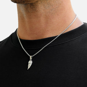 Man wearing a black shirt with a silver necklace featuring a feather pendant.