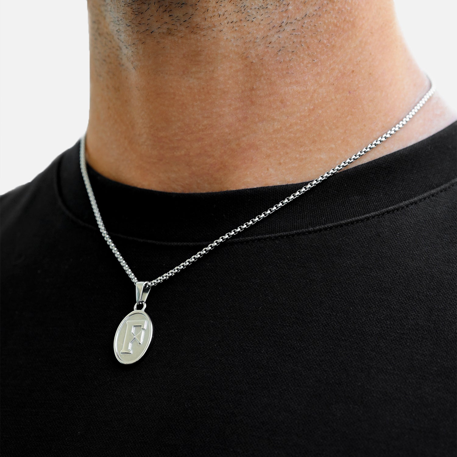 Silver necklace with a pendant on a person wearing a black shirt.