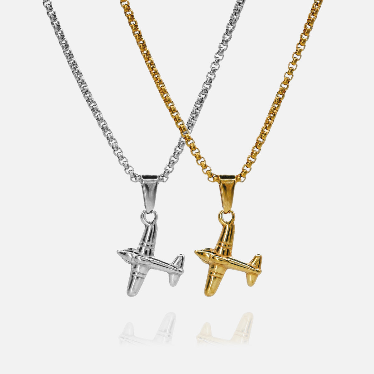 Two airplane-shaped pendants on chains, one silver and one gold, on a white background.