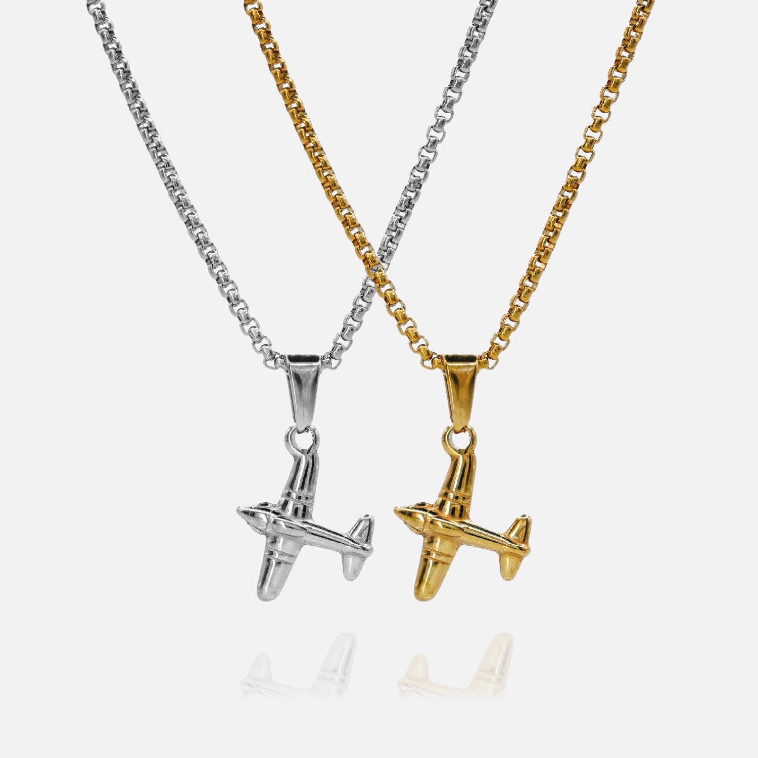 Two airplane-shaped pendants on chains, one silver and one gold, on a white background.