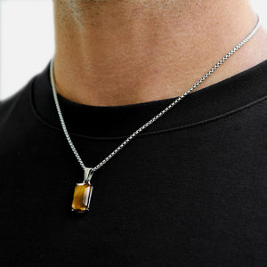 Necklace with a rectangular pendant worn by a person on a black shirt