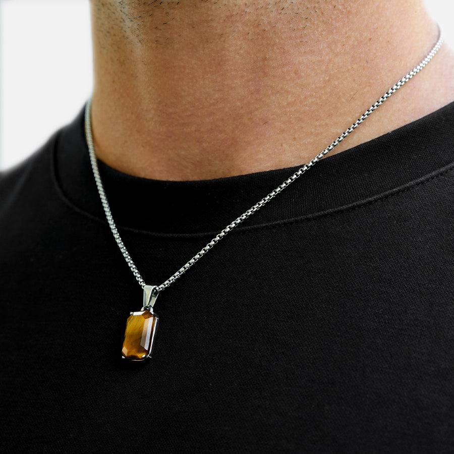 Necklace with a rectangular pendant worn by a person on a black shirt