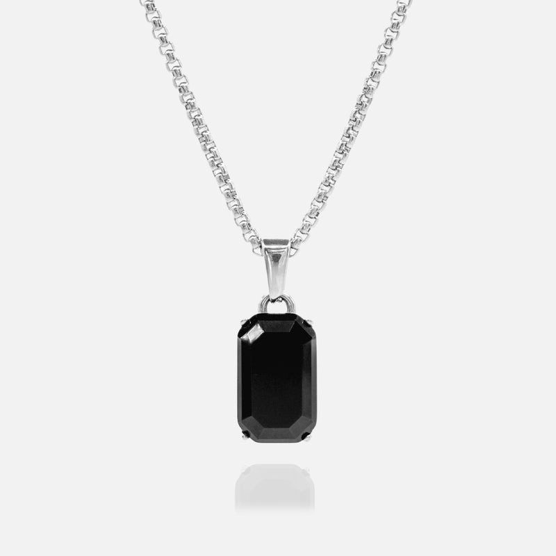 Black gemstone pendant on a silver chain against a white background