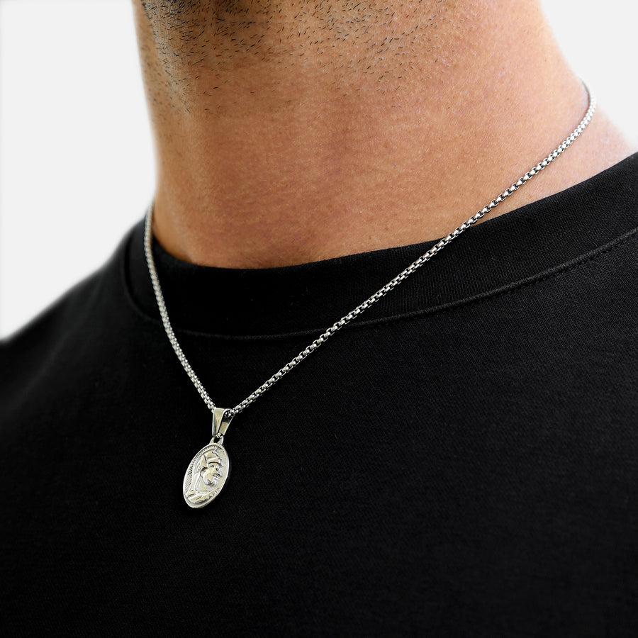 Silver necklace with a pendant on a person wearing a black shirt.