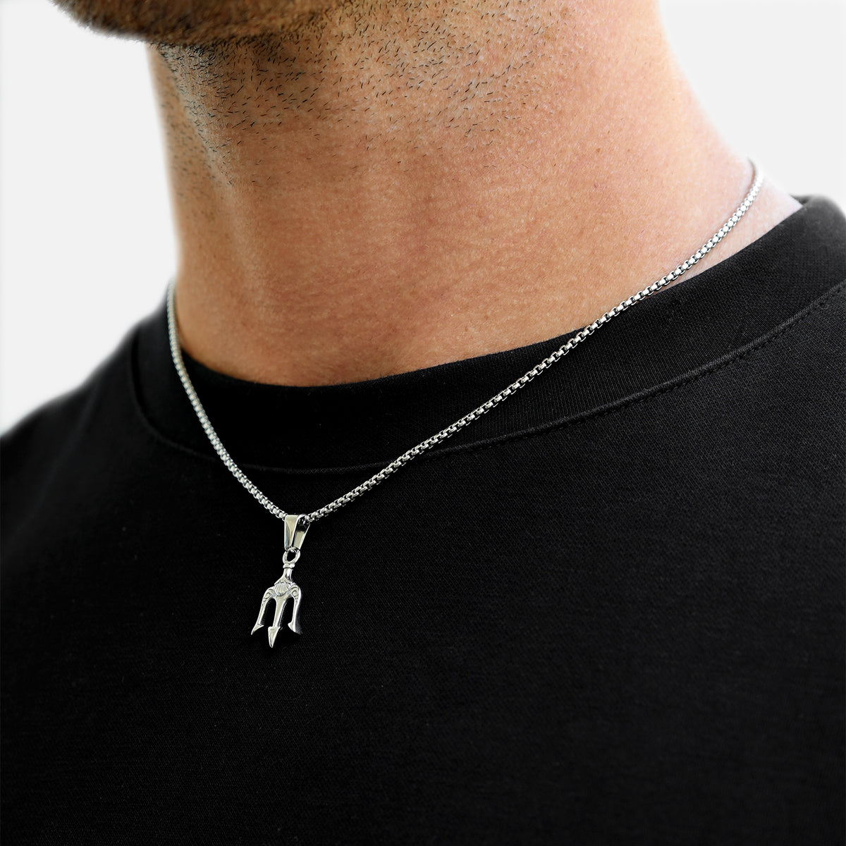 Silver necklace with a pendant worn by a person on a black shirt