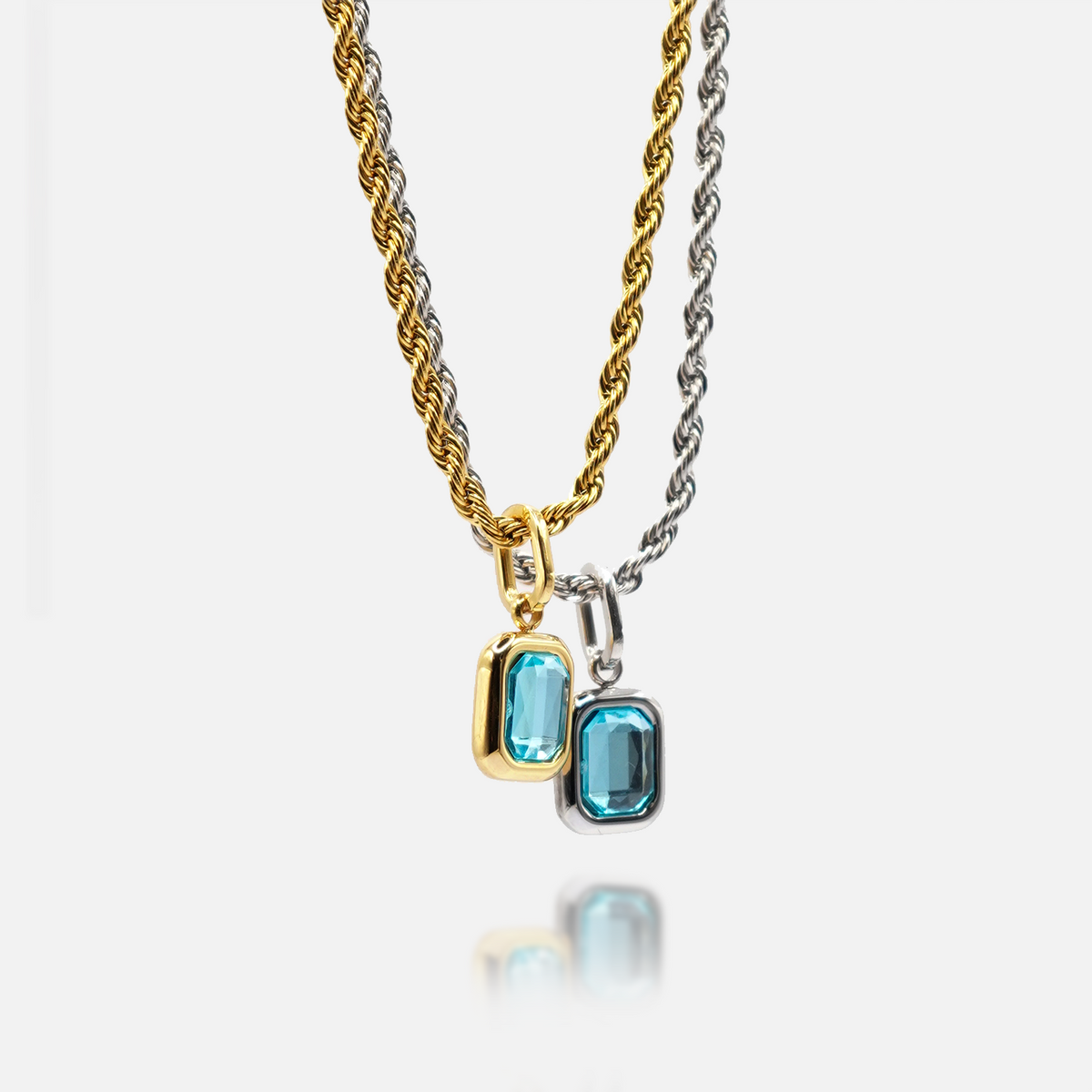 FRNE glacier blue gemstone pendant necklaces in gold and silver finishes, featuring rectangular light blue stones on twisted chains, displayed side by side on a clean white background