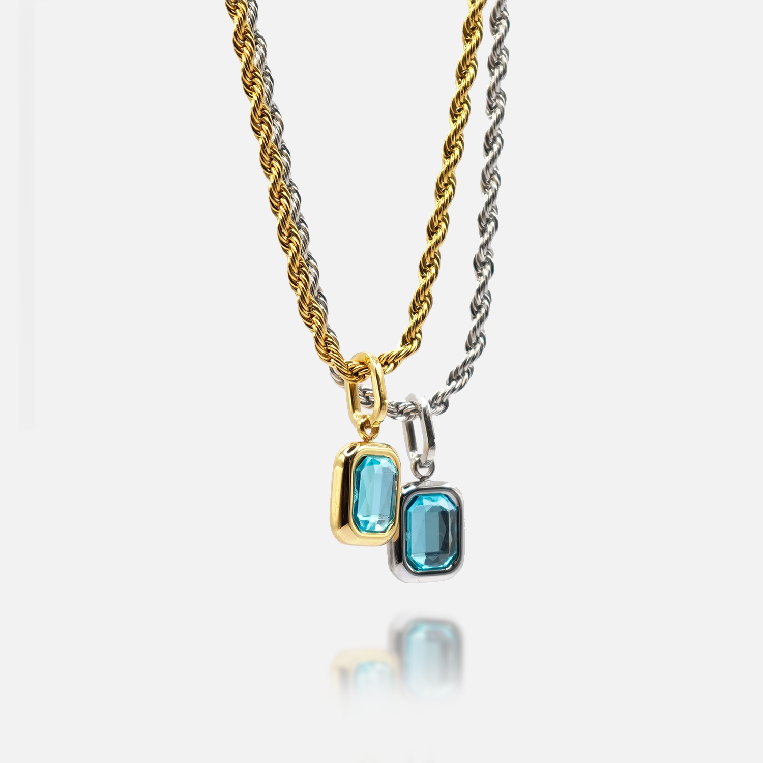 FRNE glacier blue gemstone pendant necklaces in gold and silver finishes, featuring rectangular light blue stones on twisted chains, displayed side by side on a clean white background