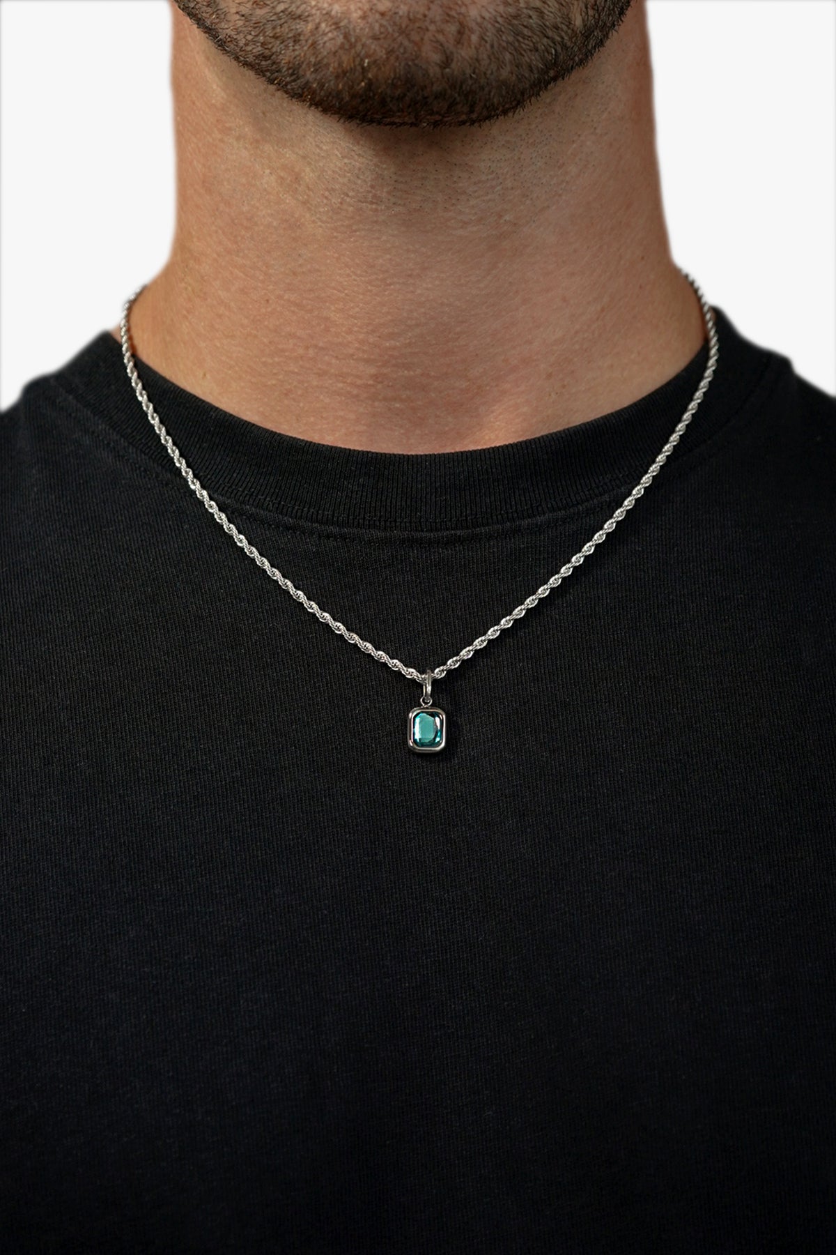 FRNE glacier blue gemstone silver pendant necklace worn by a person, featuring a rectangular light blue stone on a silver chain styled against a black t-shirt for contrast